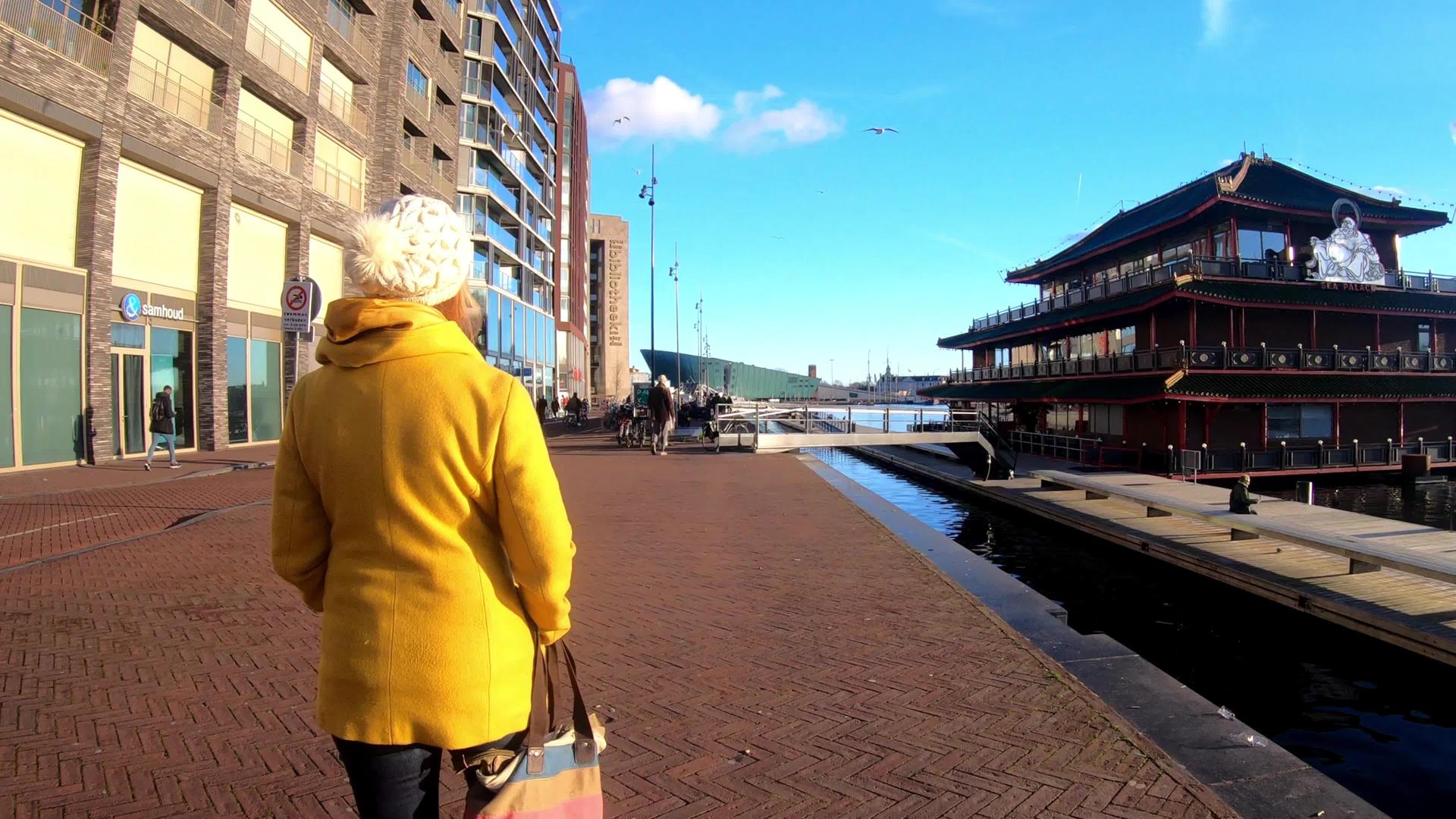 妇女穿过阿姆斯特丹运河游客探索阳光明媚的阿姆斯特丹日视频的预览图
