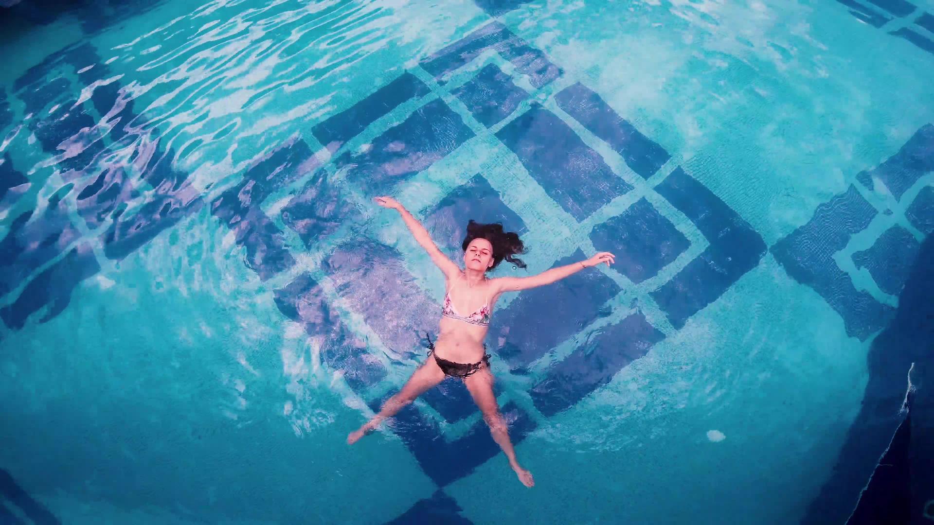 比基尼女孩躺在游泳池的水面上视频的预览图