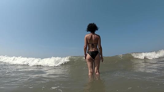 女人在海边玩耍海浪缓慢地挥舞着海浪视频的预览图
