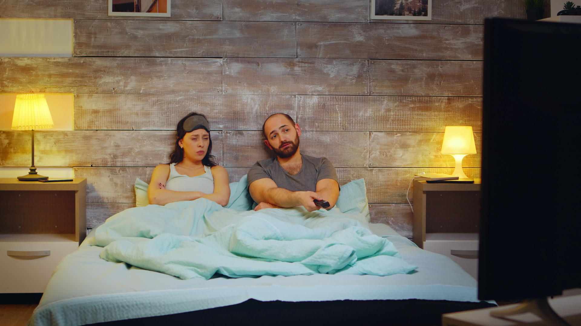 晚上夫妻俩用电视遥控器在卧室选择节目视频的预览图