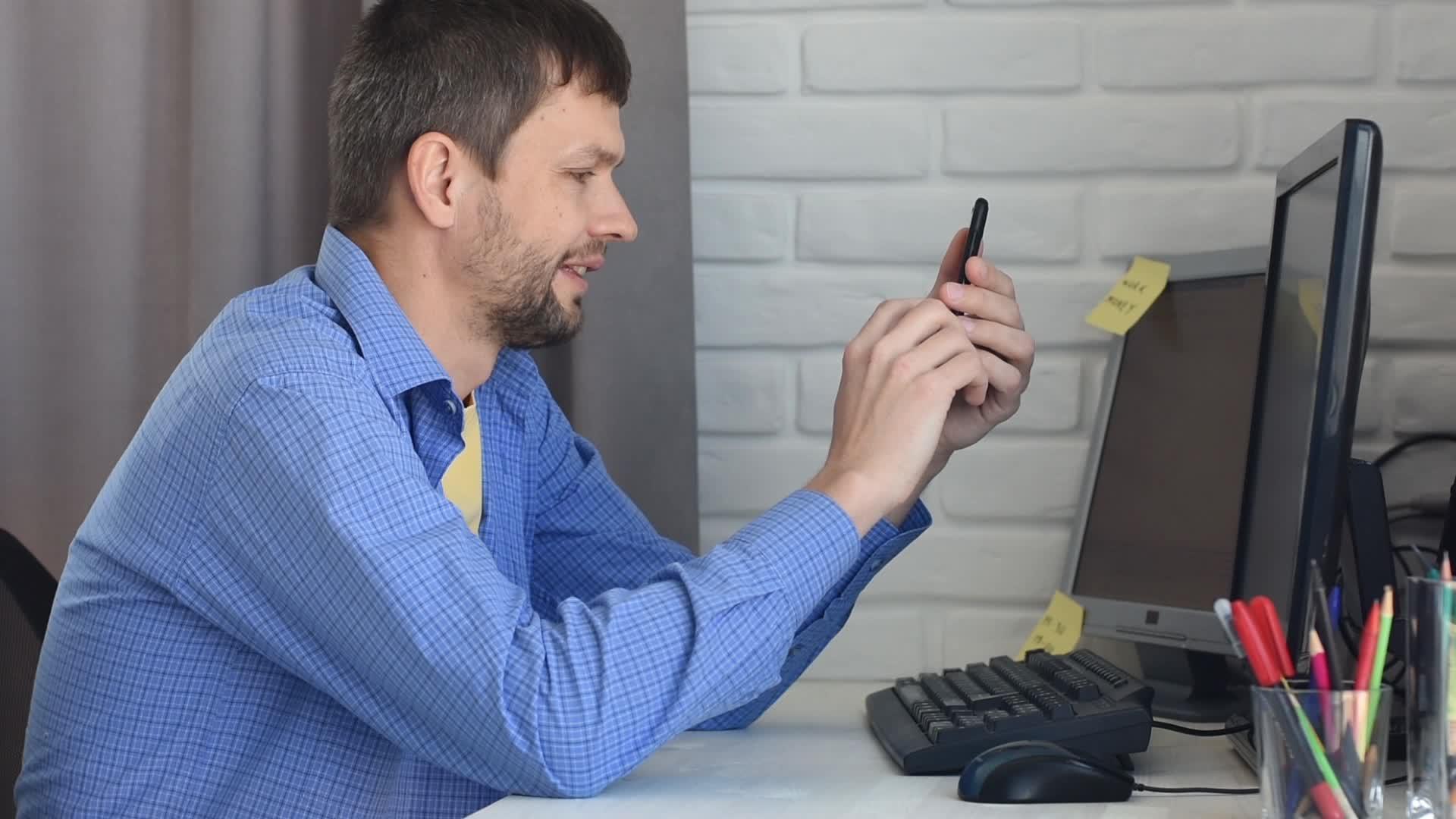 一名男子坐在桌子上通过电话和视频交流进行交流；以及视频的预览图