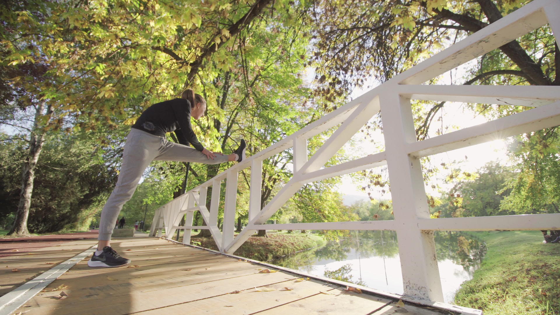 女孩在木桥栅栏上伸展双腿以加热跑步运动视频的预览图