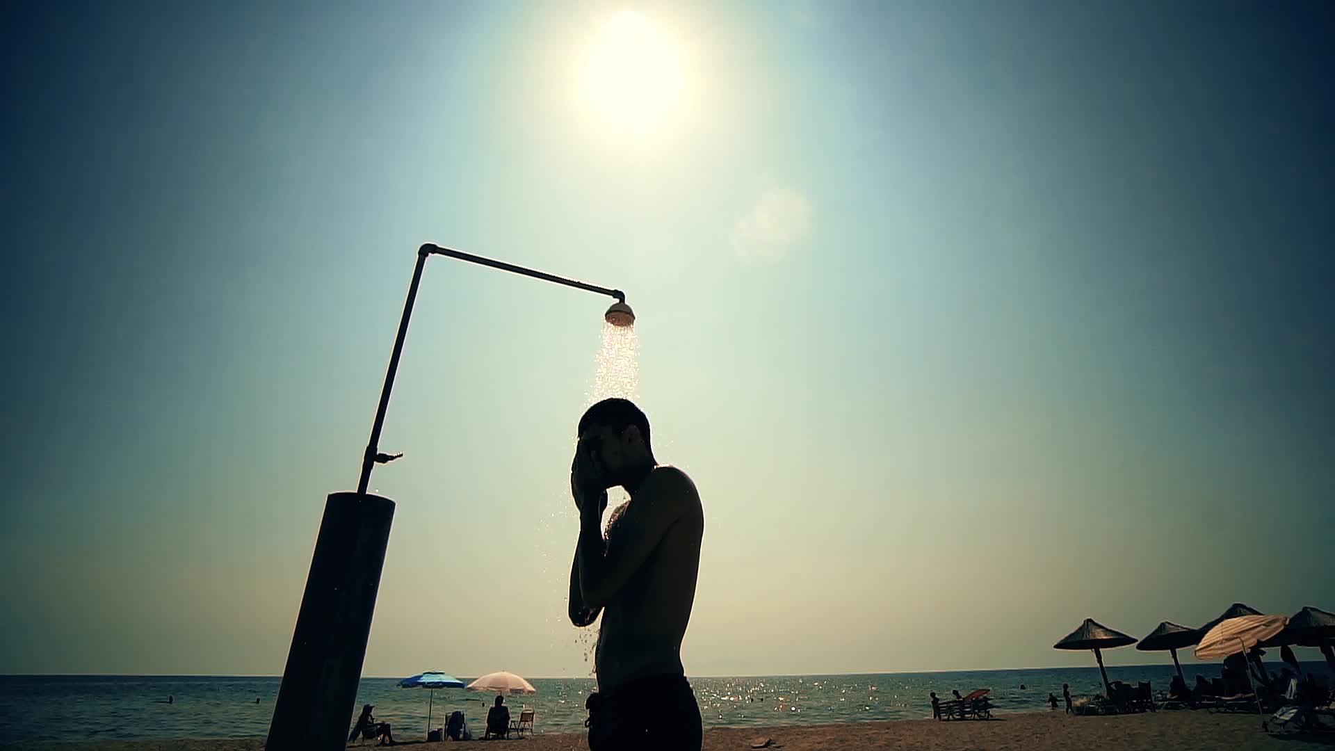 年轻人在海滩淋浴下洗头慢动作视频的预览图