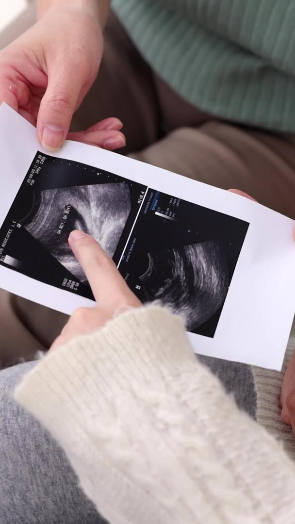 年轻的孕妇和婆婆一起看孕检b超视频的预览图