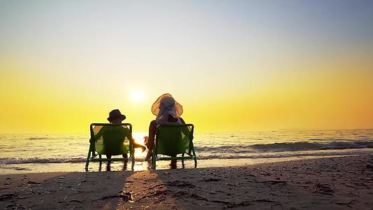 母亲和儿子戴着帽子暑假期间在海滩上享受奢华的日落视频的预览图