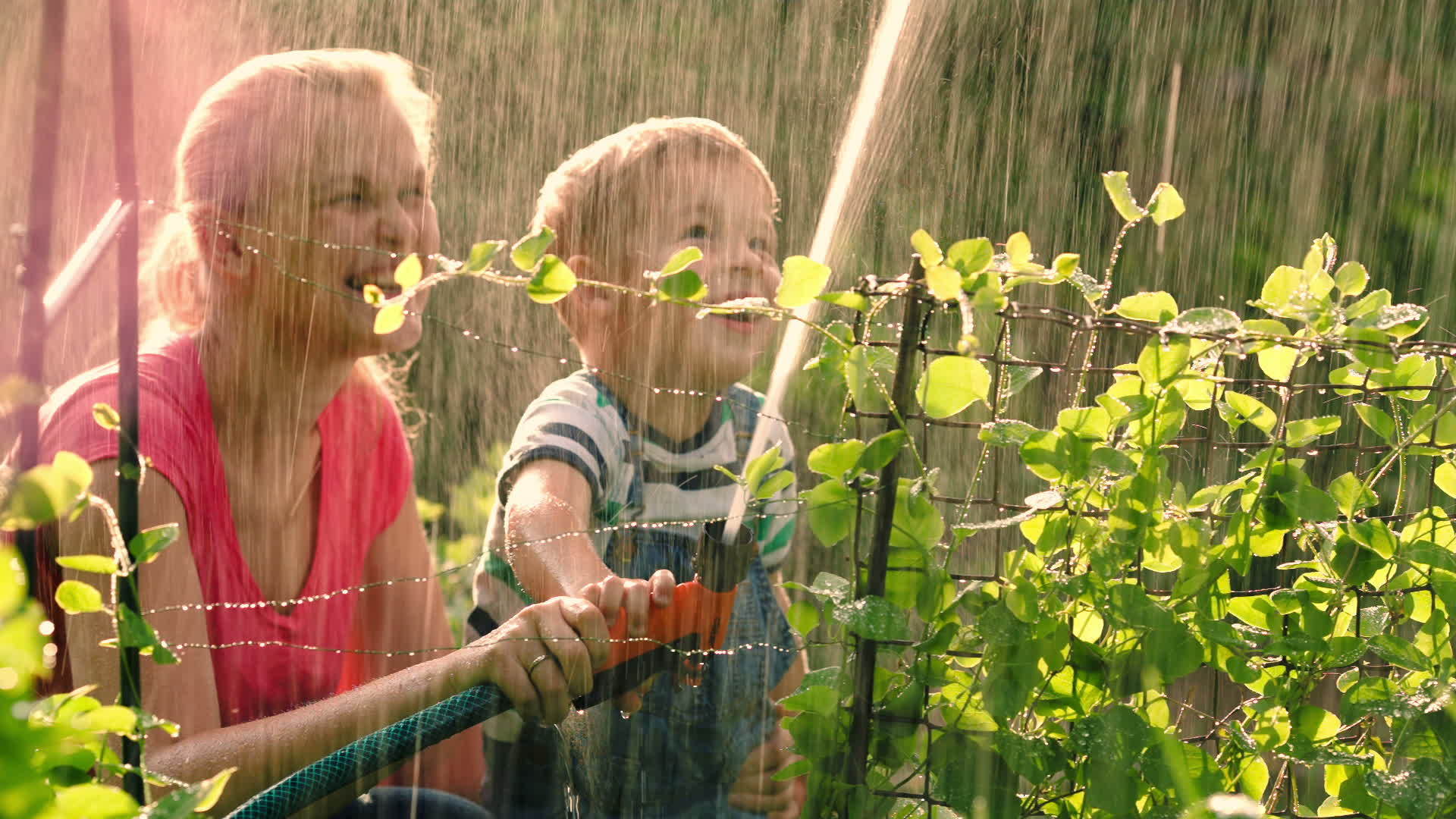母亲帮助儿子用水龙头给花园浇水视频的预览图