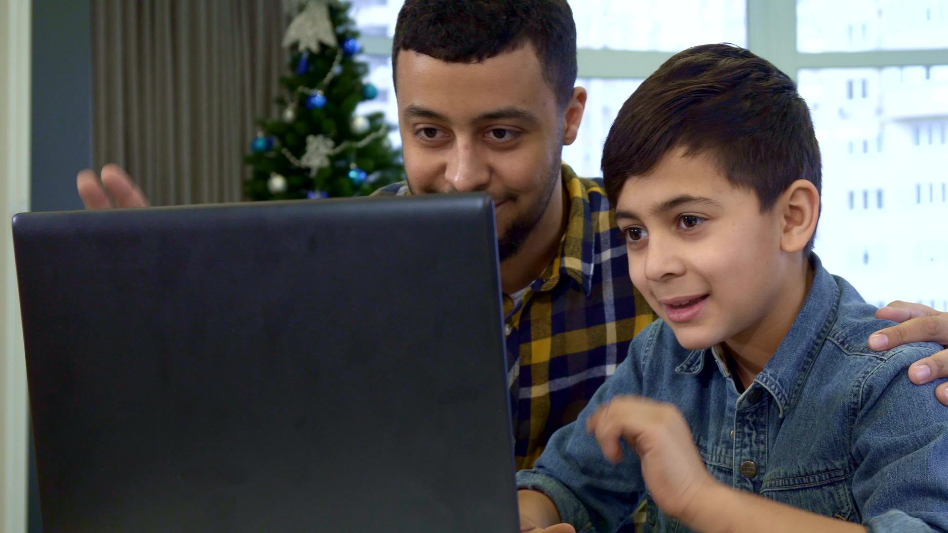 父亲和儿子在笔记本电脑上挥手视频的预览图