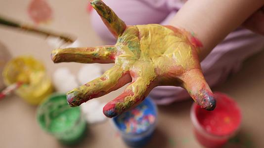 蹒跚学步的孩子的手指上涂满了油漆视频的预览图