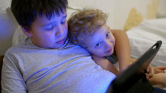 两个男孩在床上玩游戏另一个在看视频视频的预览图