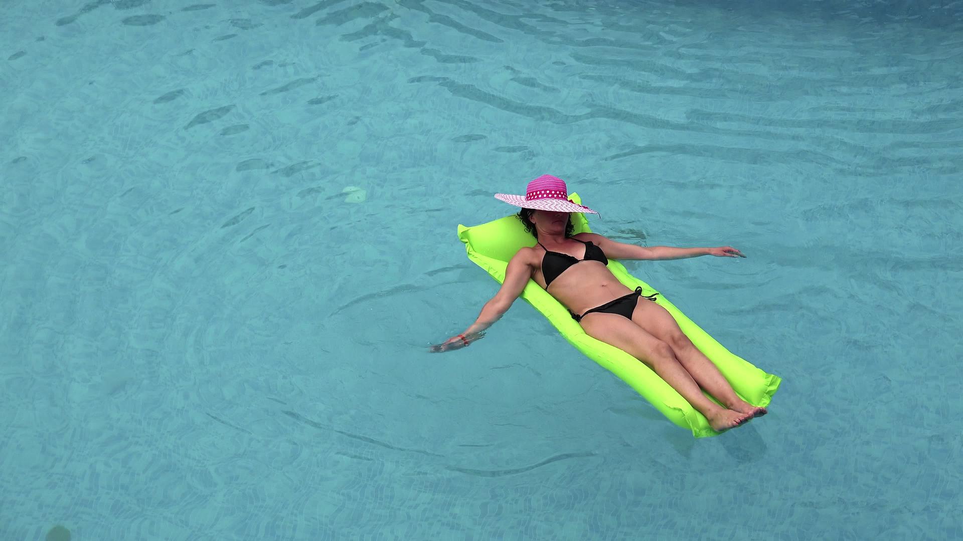 女性在海滩游泳池的充气床垫上放松视频的预览图