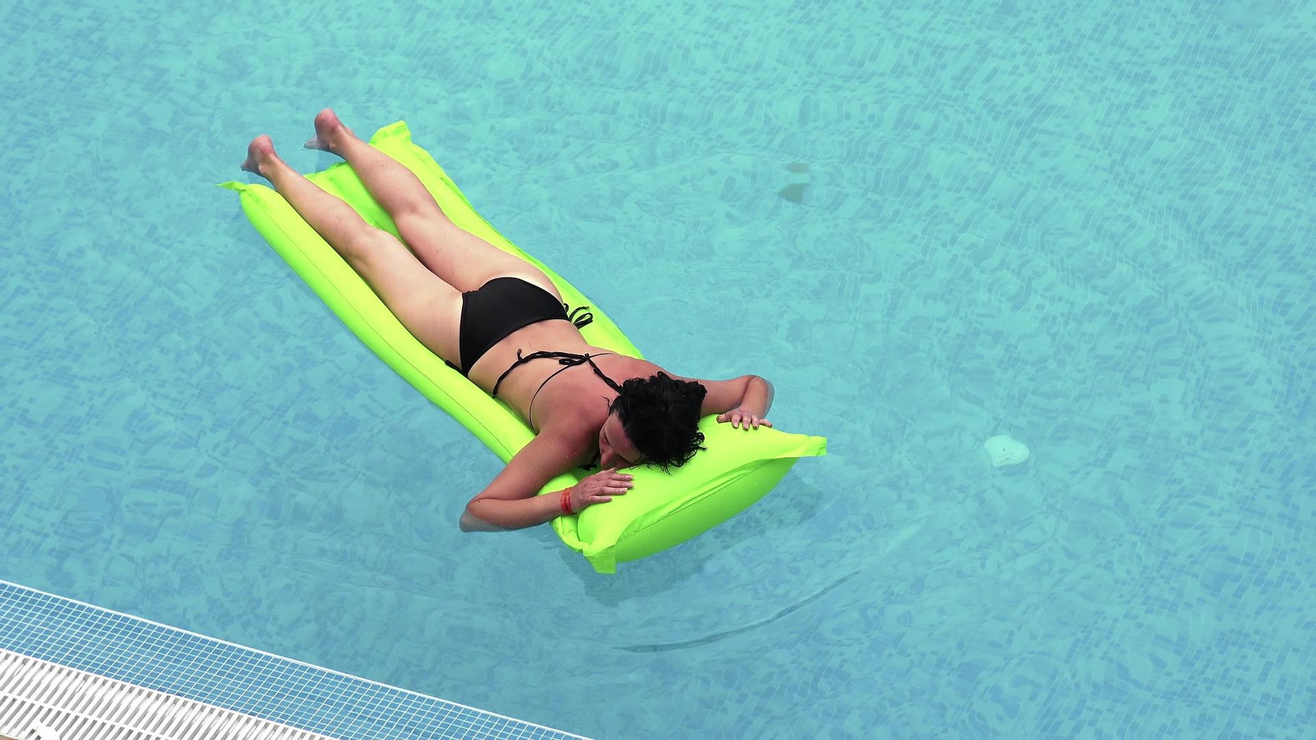 女孩在游泳池里的绿色充气床垫上游泳视频的预览图