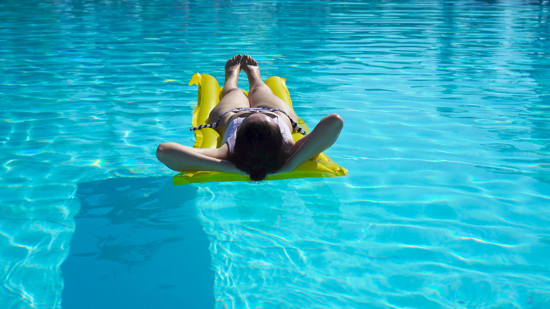 年轻女子在户外游泳池用空气床垫放松视频的预览图