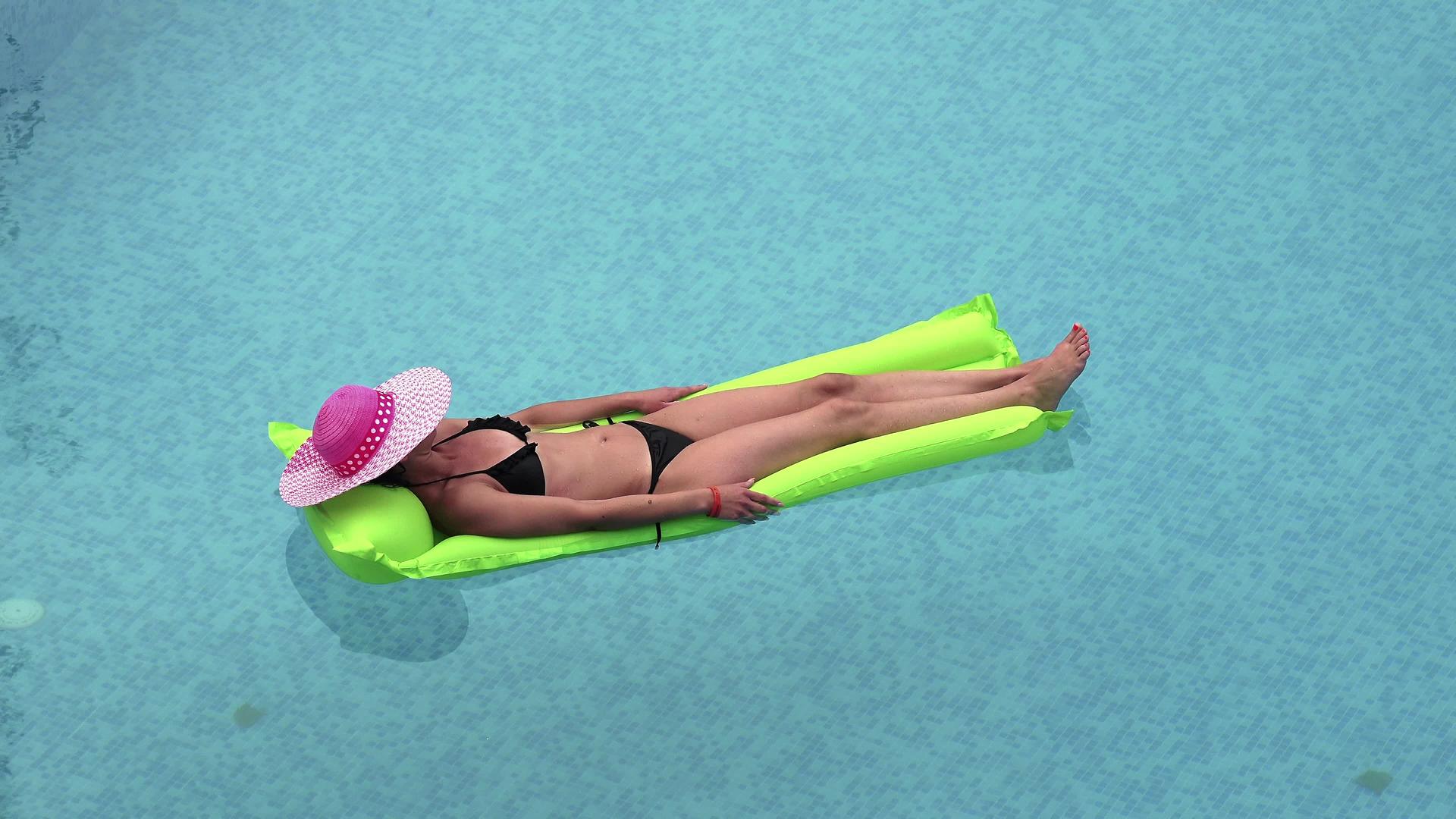 性感的女孩漂浮在海里或游泳池的床垫上视频的预览图