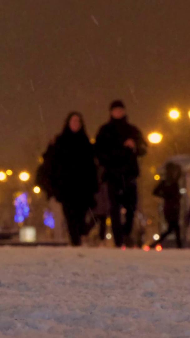 冬季下雪的夜晚城市低角度拍摄行人视频的预览图
