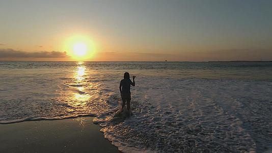 日落时分在海边玩水的人高清视频视频的预览图