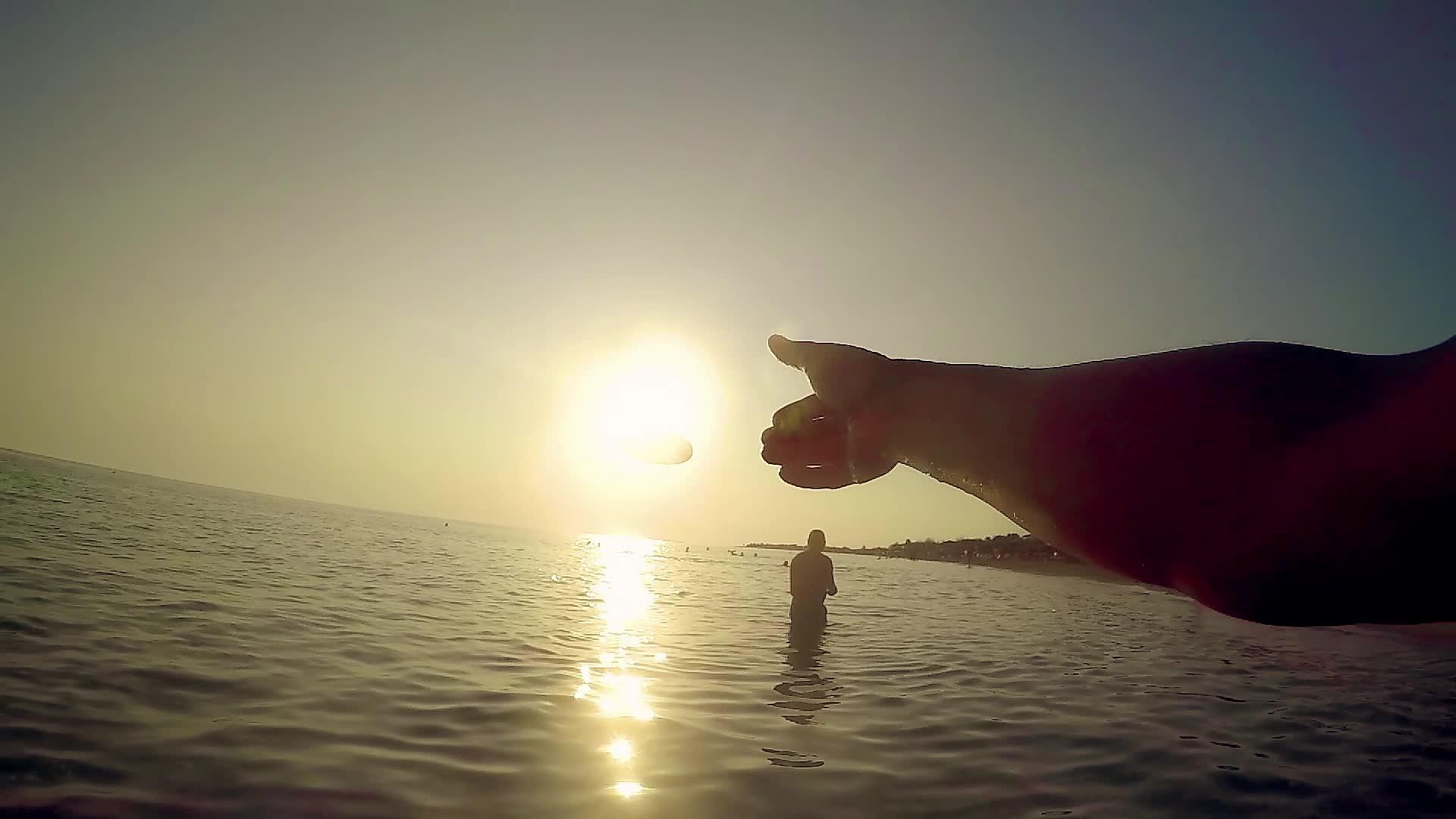一只手在沙滩上扔一个飞盘夏天日落夏天视频的预览图