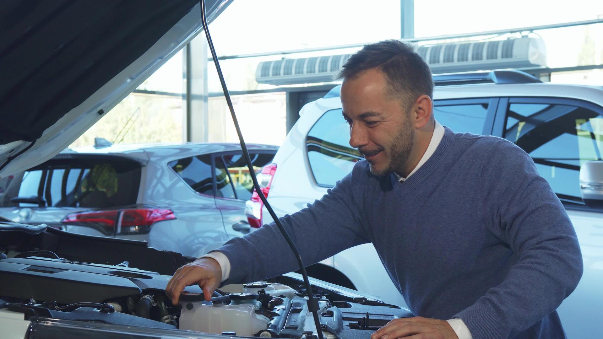一个快乐的人打开汽车的引擎盖研究汽车里的东西视频的预览图
