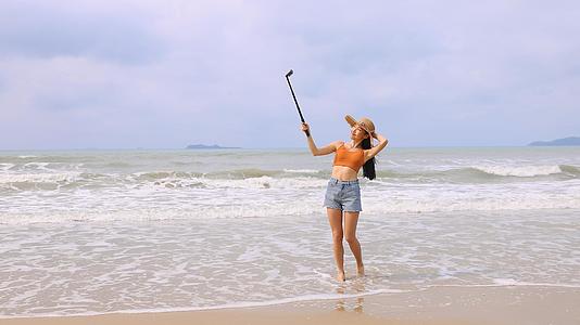 海边美女使用自拍杆拍摄景象视频的预览图