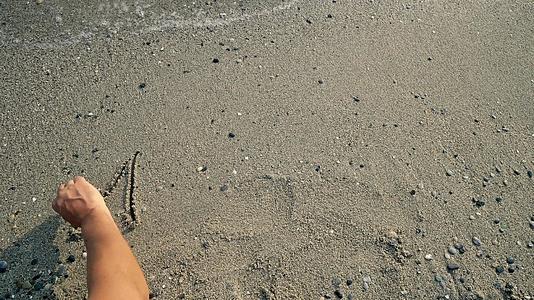 用手写一个字海滩上的古石被海浪冲洗视频的预览图