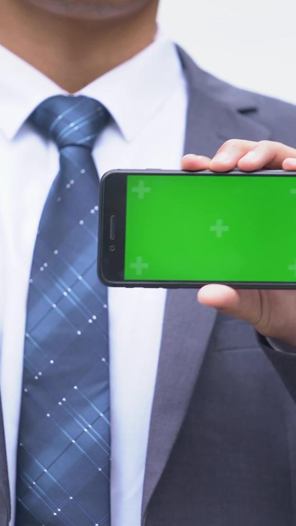 穿西装的办公男生展示绿幕手机视频的预览图