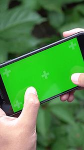 穿西装的男士玩绿屏手机视频的预览图