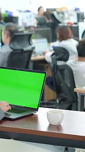 商务办公男性边喝咖啡边使用绿屏电脑视频的预览图