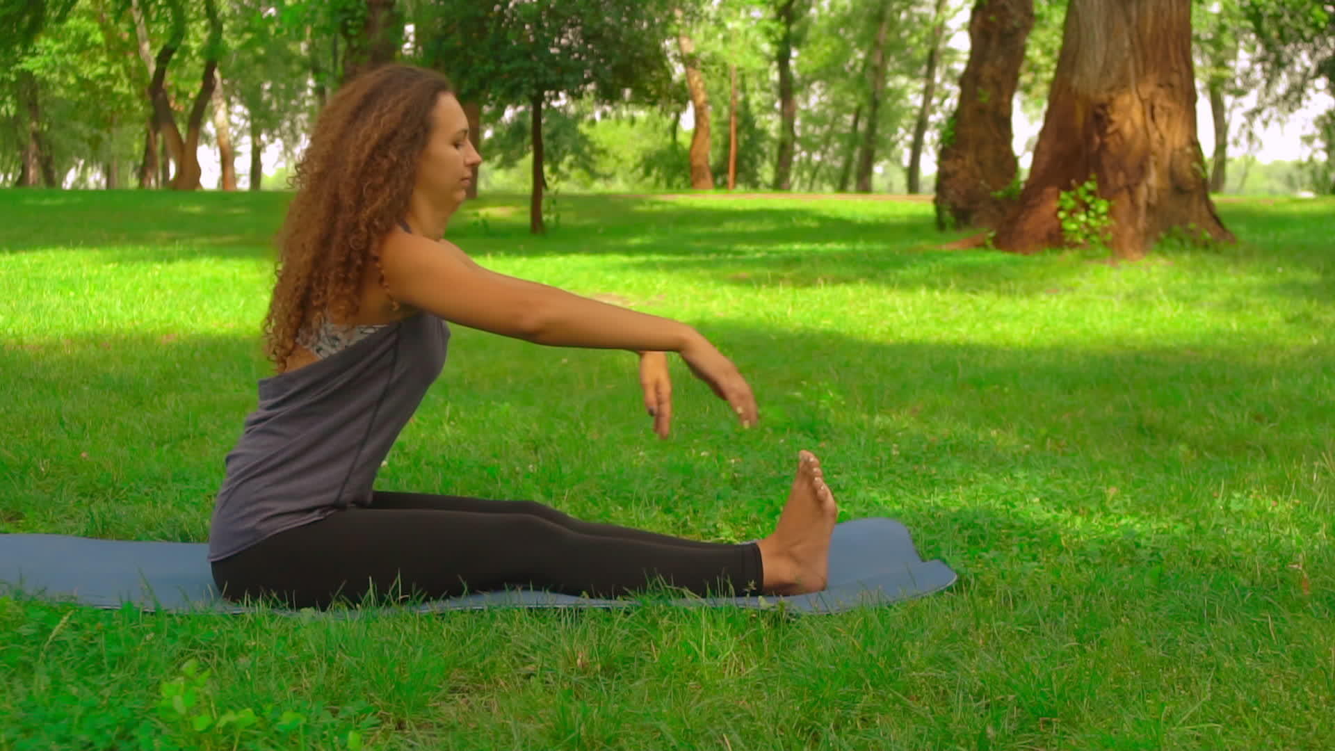 瘦女人在公园里做前弯姿势视频的预览图