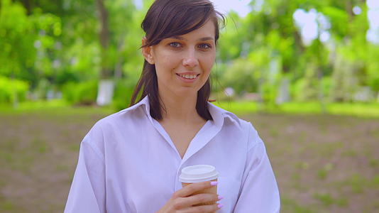 年轻女性在街上喝咖啡 穿着白衬衫视频的预览图