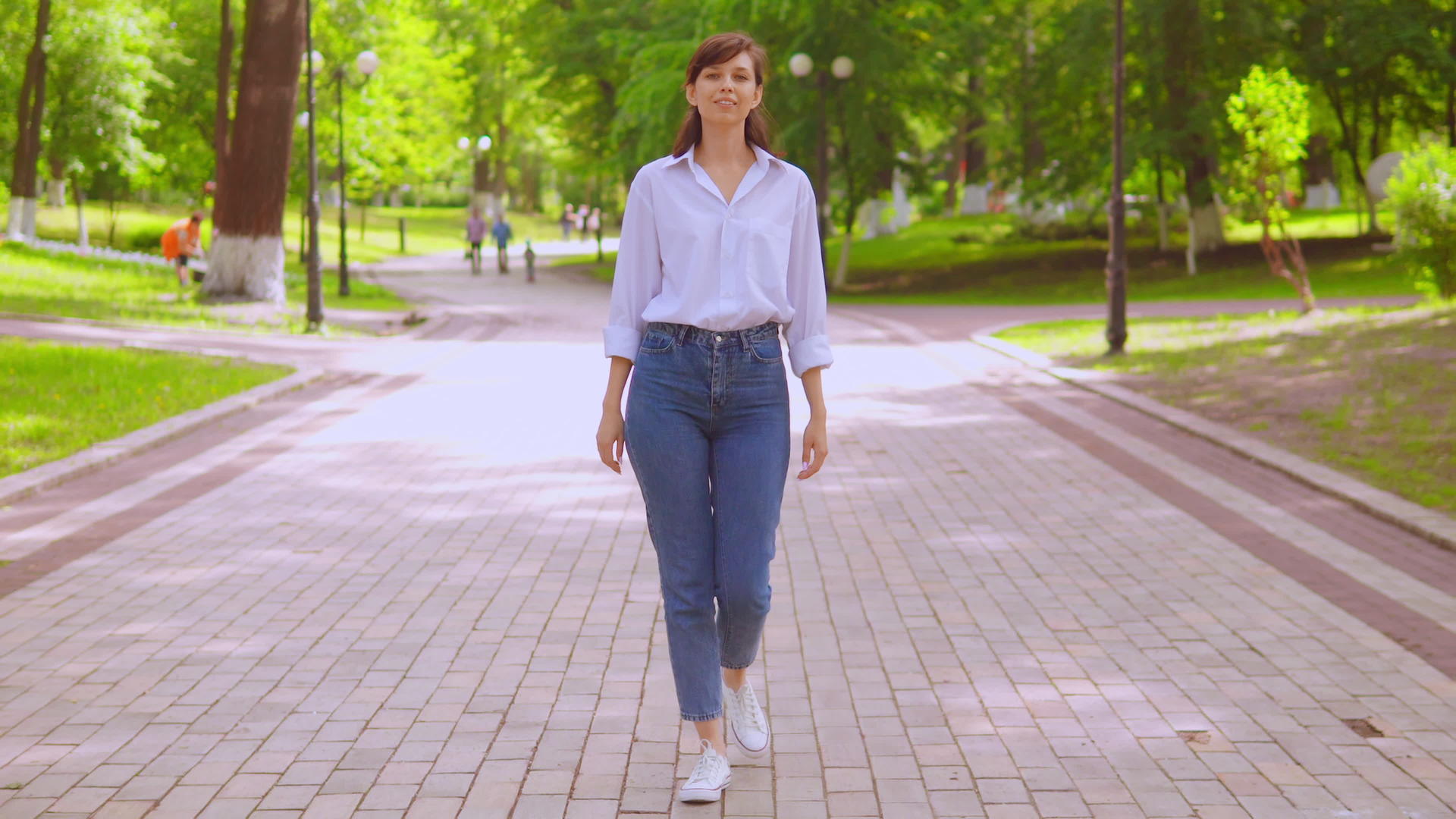 夏天穿着白衬衫和牛仔裤的年轻女子在街上散步视频的预览图