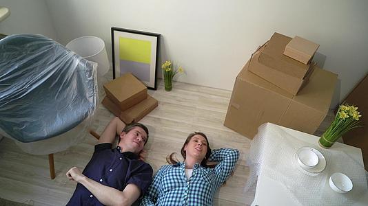 一对年轻夫妇躺在公寓的地板上休息视频的预览图