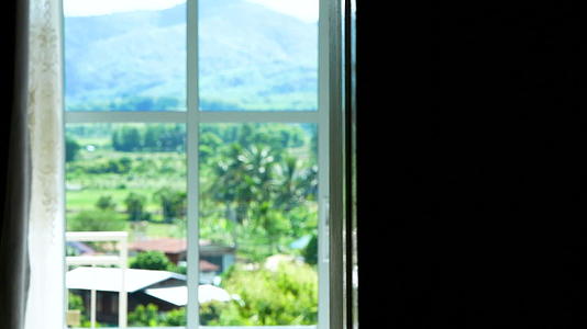透过酒店房间的窗户你可以看到山和自然的景色视频的预览图