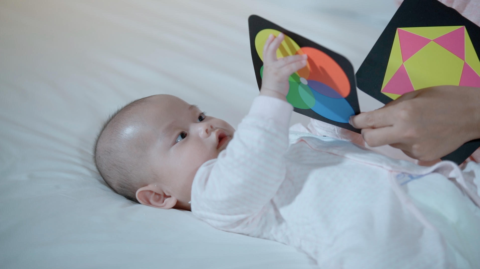 4k升格宝宝躺在床上看彩色卡片玩耍视频的预览图