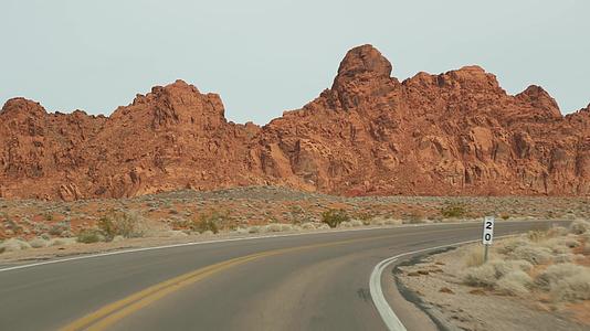 公路旅行在美国内华达州拉斯维加斯的火谷驾驶汽车在美国公路旅行红色外星岩层莫哈韦沙漠荒野视频的预览图