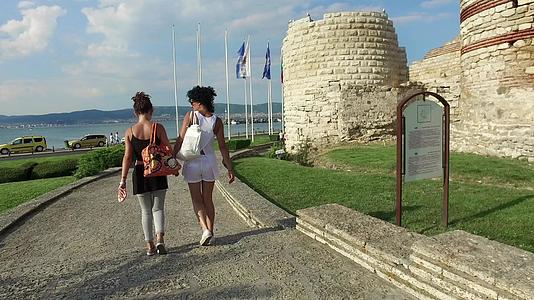 游客的母亲和女儿走在被摧毁的塔楼附近在古老的内塞巴镇周围筑石墙视频的预览图