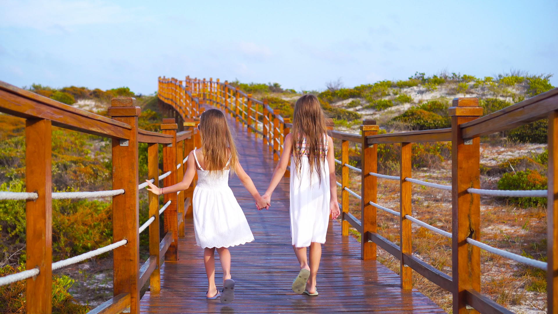 可爱的小女孩在去白色热带海滩的路上在木桥上视频的预览图