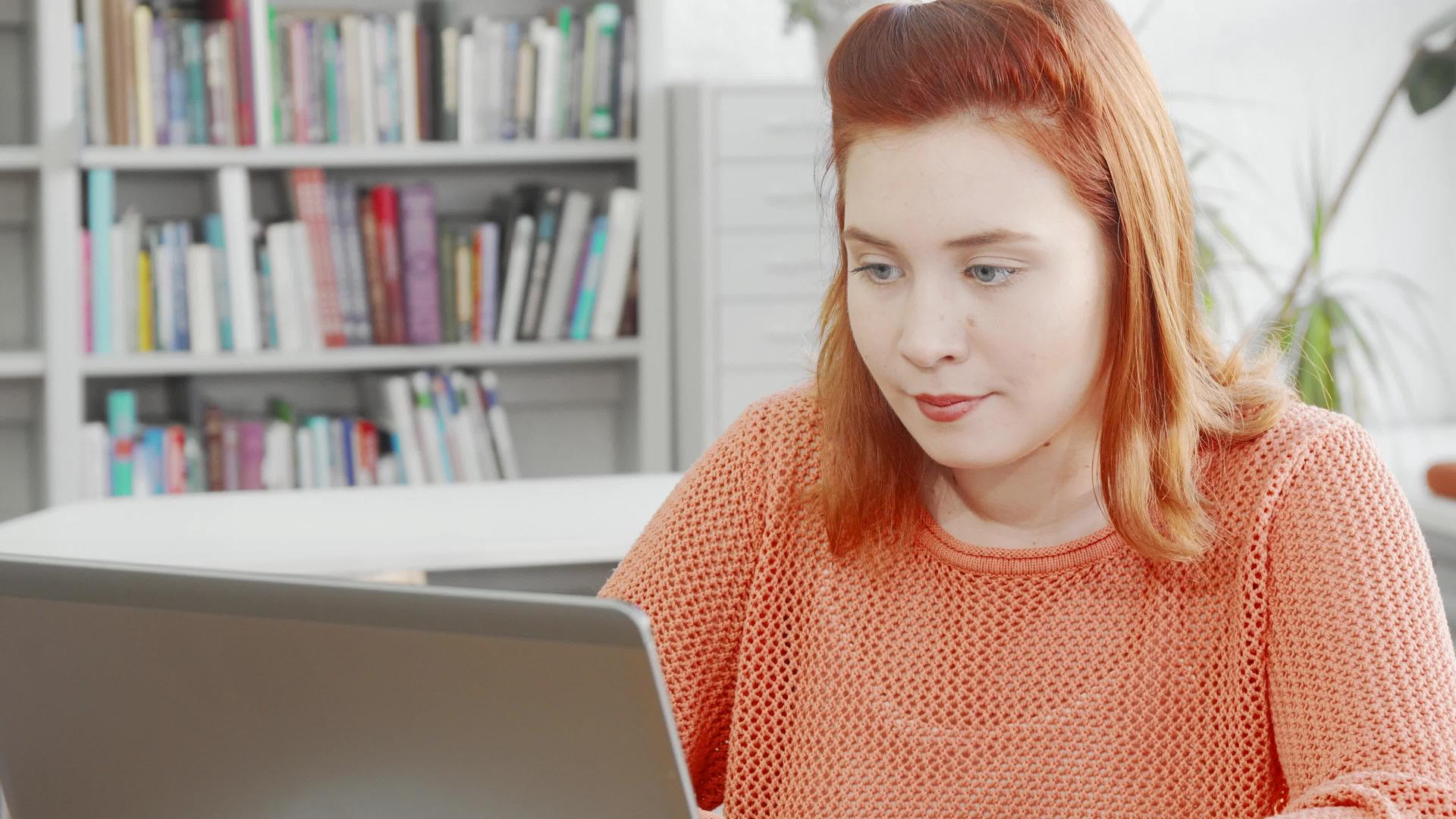 年轻女性在图书馆用笔记本电脑工作视频的预览图