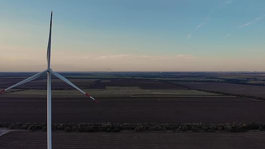 乡村风力涡轮机发电厂和农田夏季黄昏空中观察视频的预览图