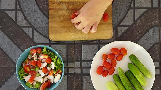 顶部视图的人在厨房桌子上切新鲜蔬菜做沙拉 切西红柿 用新鲜蔬菜做维生素沙拉视频的预览图