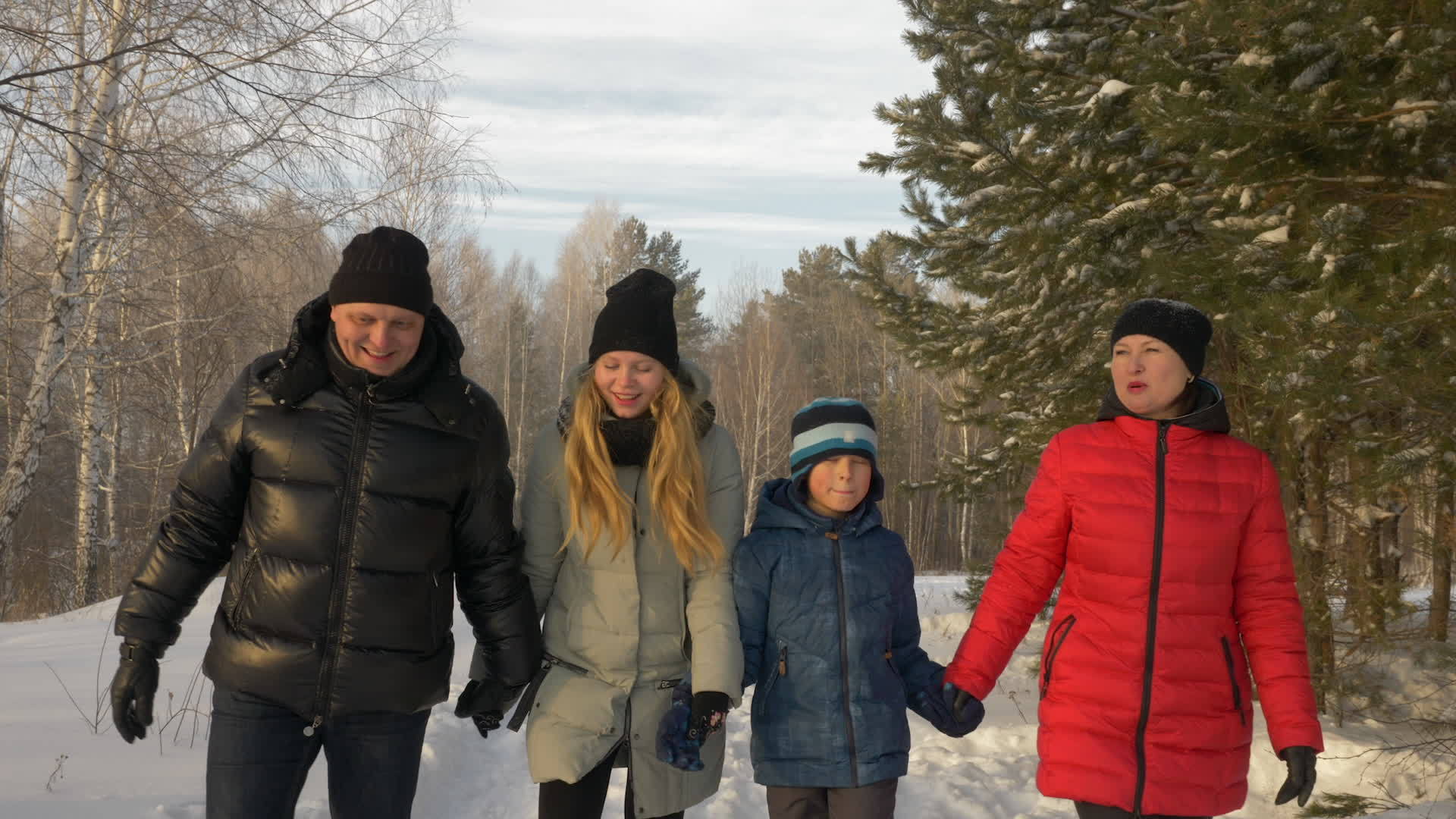在寒冷的冬天友好的家庭在雪林中握手视频的预览图