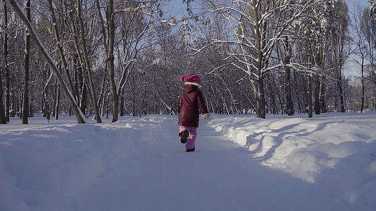 女孩在冬天的公园里跑来跑去视频的预览图