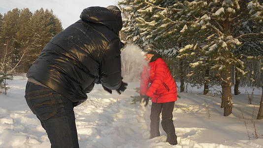 男人和女人在冬天在雪林中散步时扔雪球视频的预览图