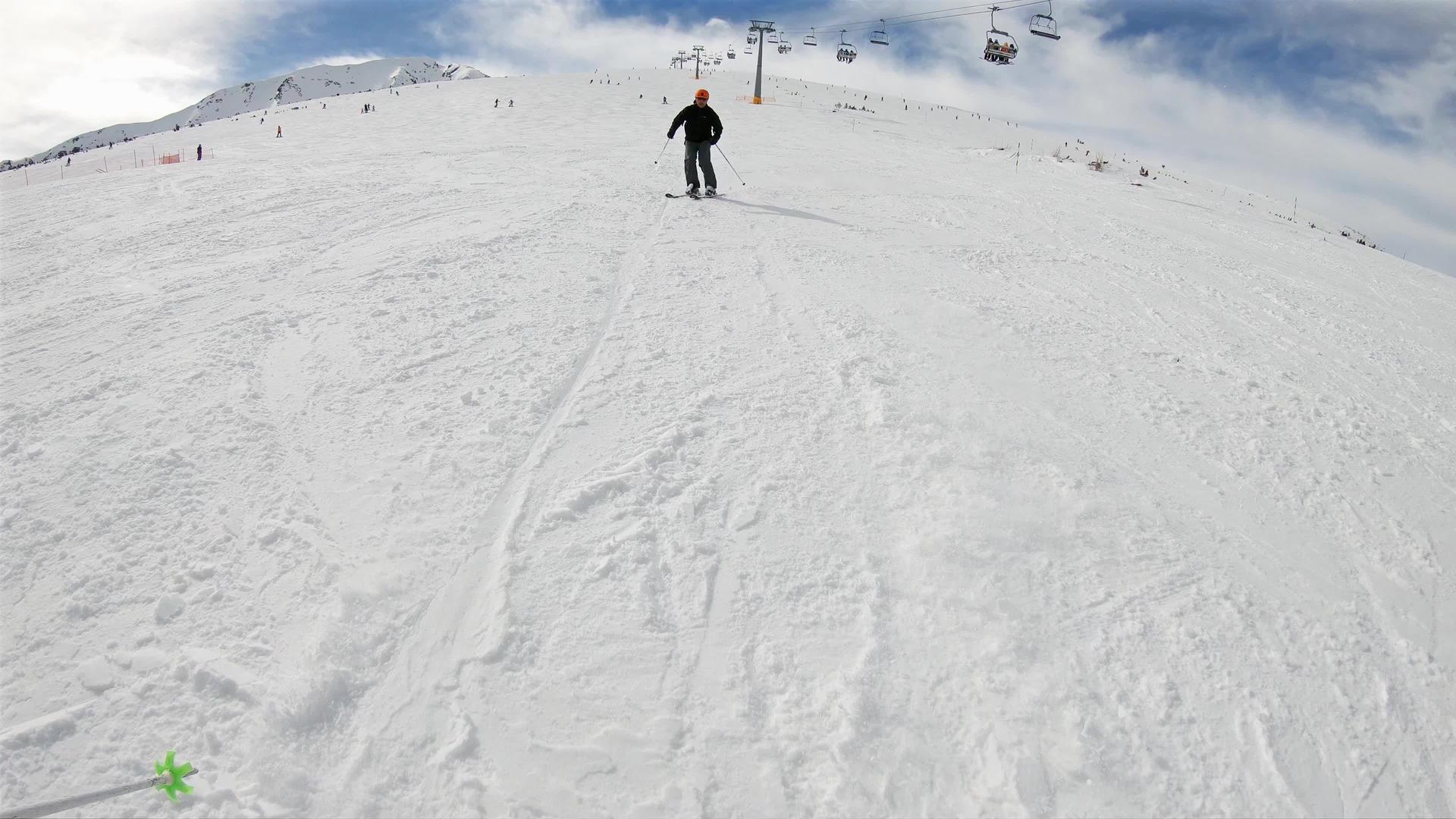 在阳光明媚的日子里保加利亚山区的高山滑雪者在相机后面的斜坡上滑雪视频的预览图