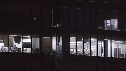 航拍城市夜晚金融互联网公司写字楼灯火通明加班的员工4k素材视频的预览图