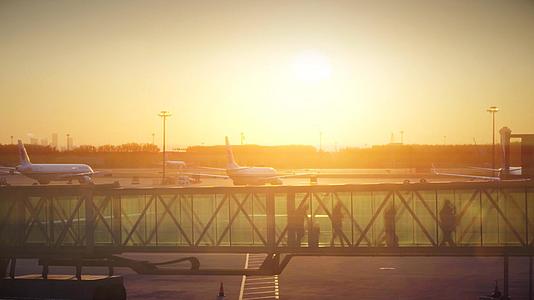 夕阳黄昏机场廊桥下飞机推着行李箱的旅客视频的预览图