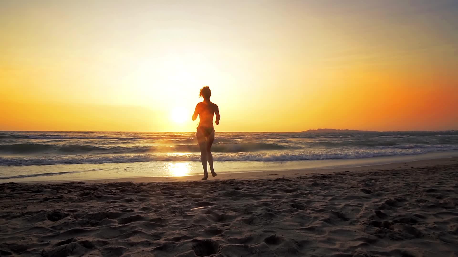 女孩在日落的海滩上慢跑视频的预览图