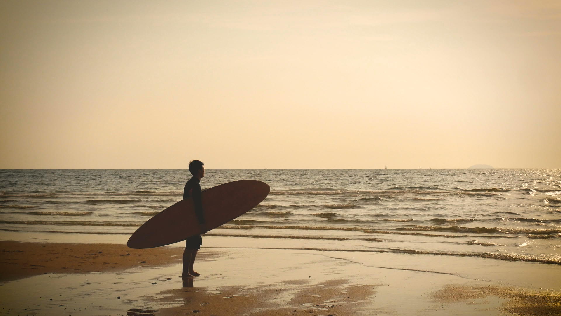 冲浪男子站在海边休眠在热带海滩日落时有长长的冲浪板视频的预览图