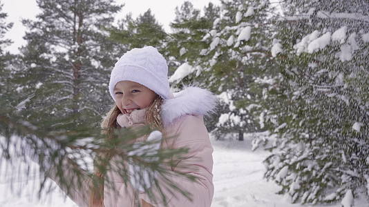 可爱的女孩在树林里的大雪下视频的预览图
