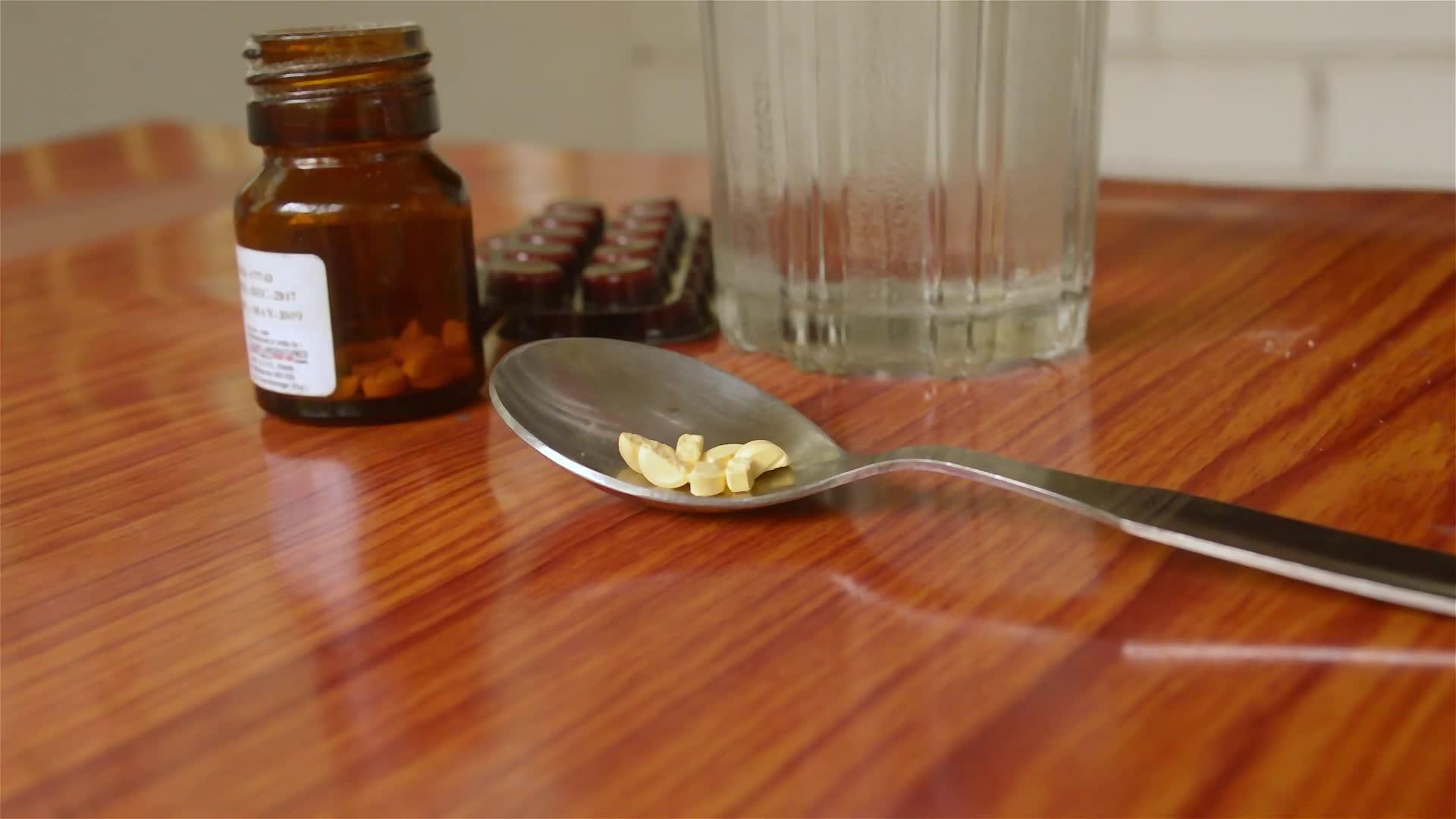 桌上放一杯水查看抗氧化剂维生素片、药丸水泡、一瓶药物和勺子中的胶囊药房主题侧视图关闭和复制空间视频的预览图