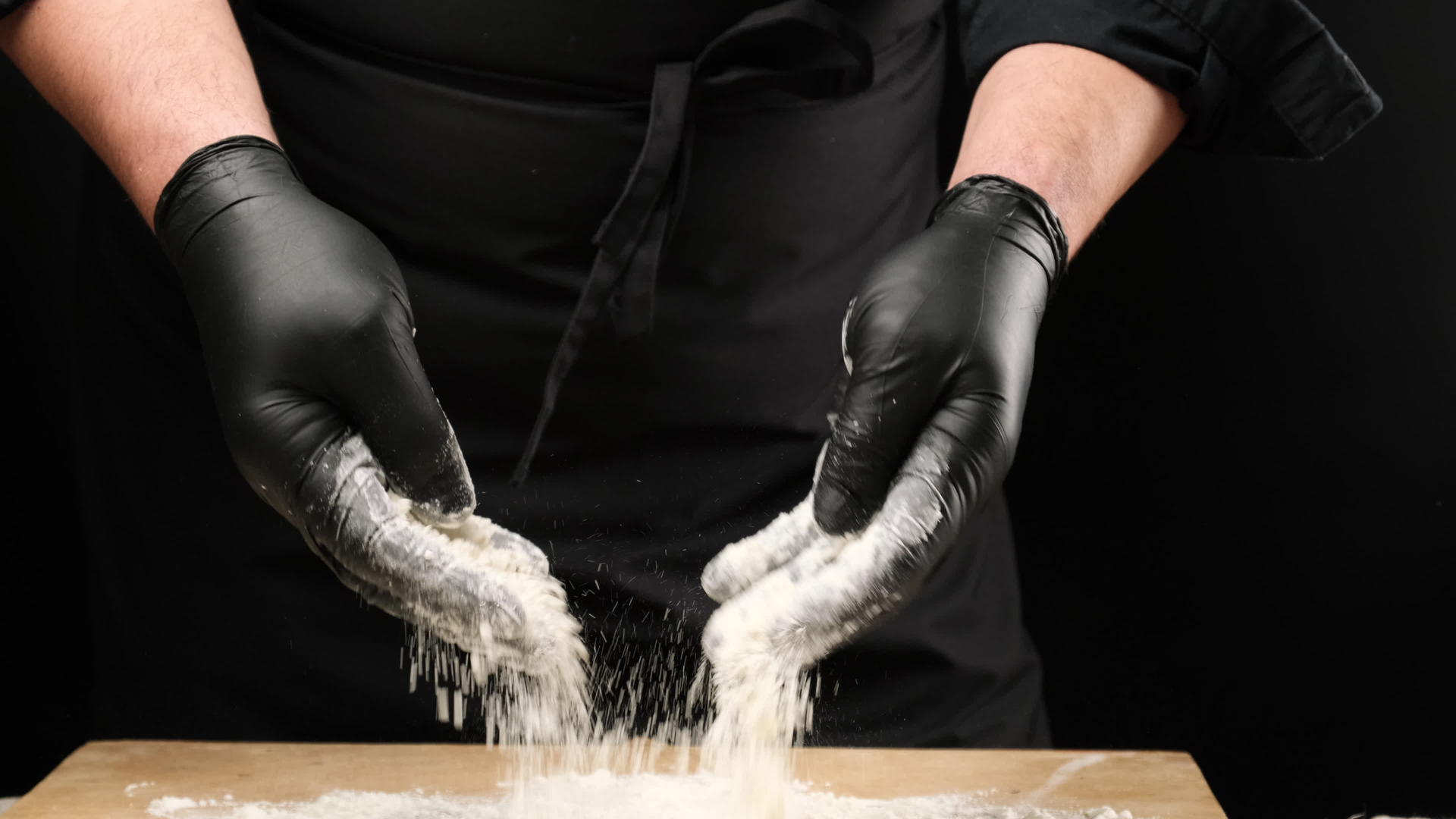 黑色乳胶手套厨师在圆木上喷洒白面粉视频的预览图