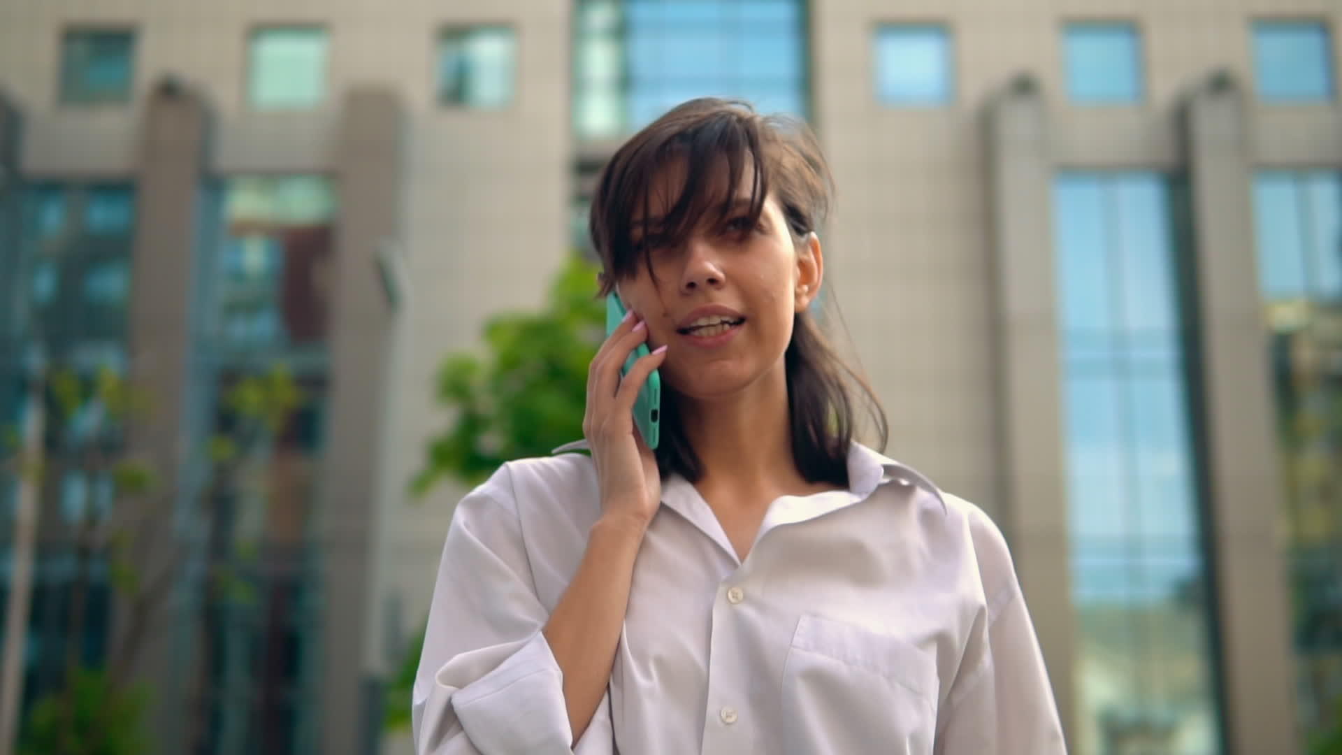 年轻女性穿着优雅的白衬衫使用手机视频的预览图